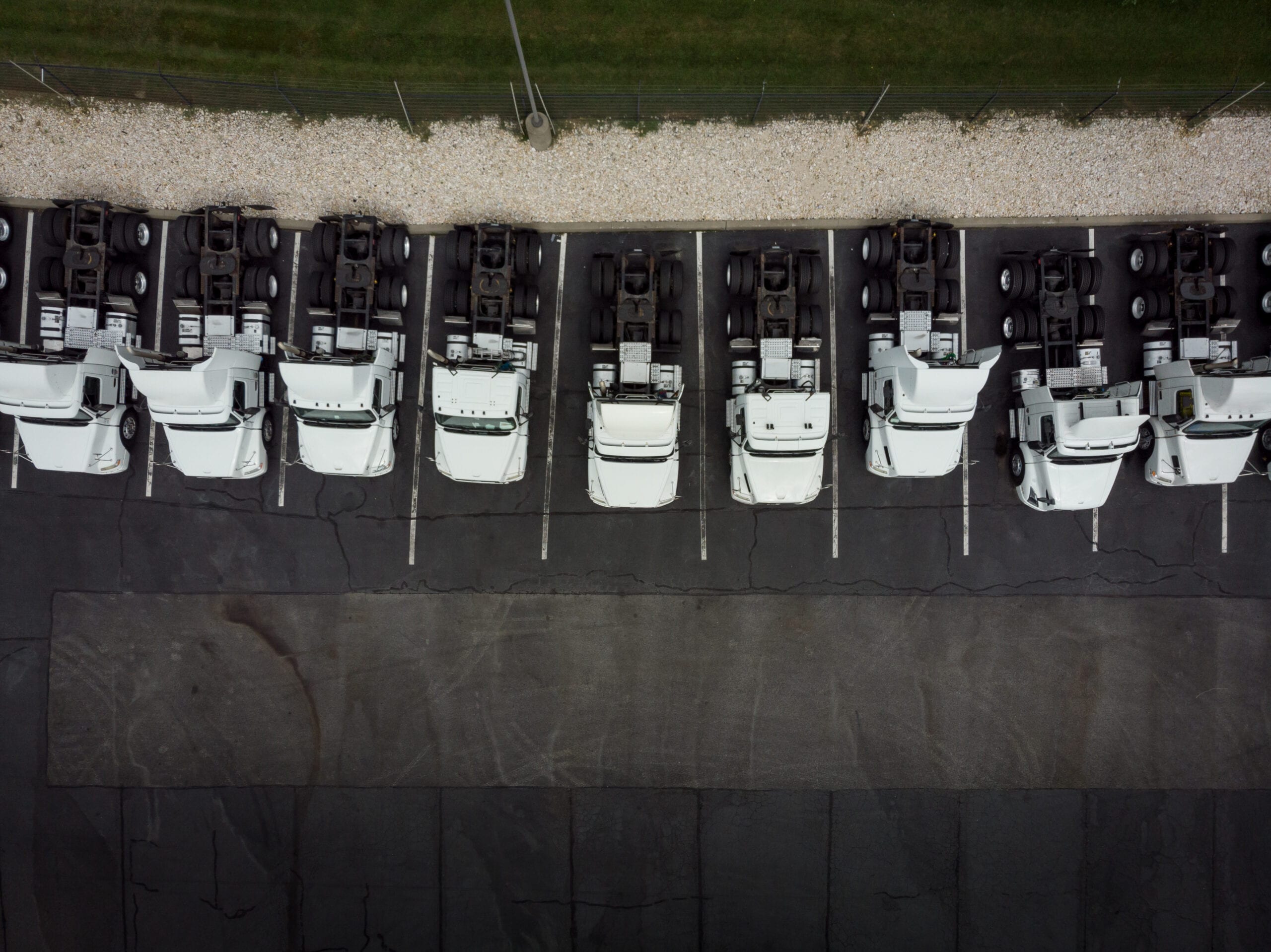 Fleet of white 18-wheeler semi-trucks overhead view drone photography